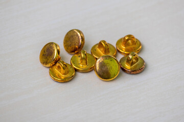 Vintage golden buttons on a wooden surface, ideal for fashion, craft, and antique themes. Perfect for designs needing a touch of old-world charm and decorative texture.