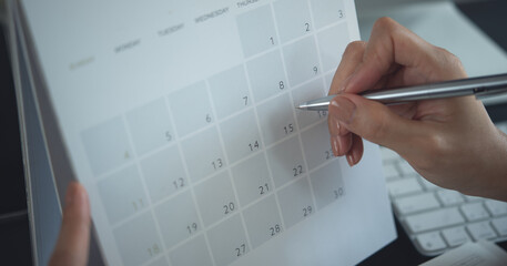 Closeup, woman hand writing on calendar event planner to set timetable organize schedule, event...