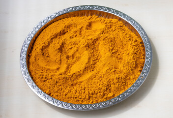 Bright yellow turmeric powder in a stainless steel dish after crushing, perfect for culinary and spice-related themes. Natural vibrant color, healthy ingredient, cooking concept.