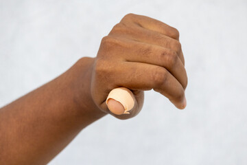 Female hand with a knife-cut thumb finger, applying an adhesive bandage. Close-up of the injured finger, showing a band-aid for the wound.