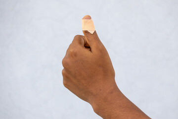 Injured female thumb finger close-up, cut by a knife, with an adhesive bandage being applied. Focus on the sticking plaster on the wounded hand, showing first aid and recovery.