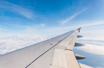 View from the airplane window at a beautiful cloudy sky and the airplane wing