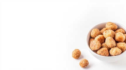 Fototapeta premium A white bowl filled with golden brown falafel balls is displayed on a bright white surface, with a few scattered around the bowl, creating an inviting scene.