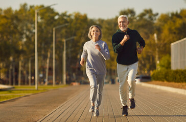 Active senior pair running, sporty physically energetic older man and woman outdoor jogging....