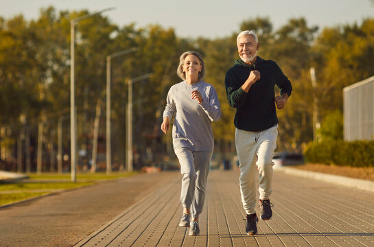 Active senior pair running, sporty physically energetic older man and woman outdoor jogging. Elderly people on street physical exercise, enjoying open air activity to boost mood, energy levels, memory