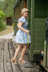 A cheerful Caucasian woman in a floral dress boards a vintage train, evoking whimsical nostalgia...