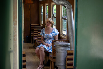 A serene Caucasian woman in a sundress, seated on a vintage train, evokes nostalgia and Railway Heritage Day  Šarganska (sharganska) osmica