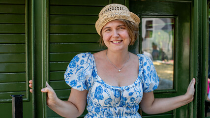 Cheerful woman in a floral dress and sunhat, evoking summer nostalgia, perfect for Midsummer...