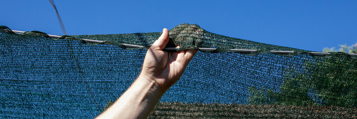 A sun-kissed hand lifts a whimsical garden net, revealing secrets beneath, perfect for Earth Day and National Gardening Week