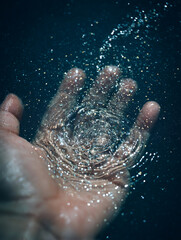 Fototapeta premium A human hand in a liquid and small ripples spread out