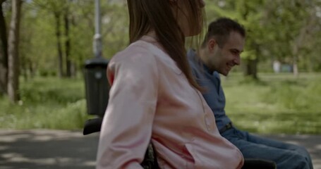 A joyful couple in wheelchairs, laughing and smiling together, navigate through a beautiful green park on a sunny day. Their friendship and positive energy highlight a vibrant, independent lifestyle. - Powered by Adobe
