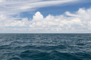 Obraz premium Ocean waves with turquoise water and white clouds