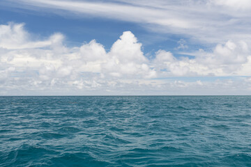 Obraz premium Ocean waves with turquoise water and white clouds