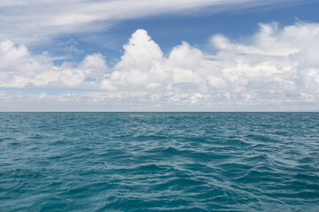 Obraz premium Ocean waves with turquoise water and white clouds