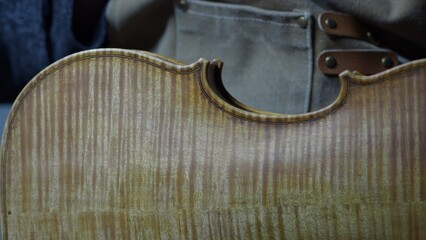 Obraz premium Skilled craftsman carefully brushing antique style varnish onto handmade violin, creating vintage patina and increasing instrument's artistic appeal