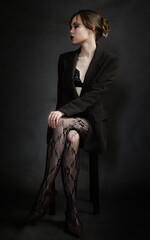 Sensual portrait of young woman in dark suit and fishnet tights.