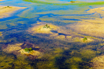 Breathtaking aerial view of the Okavango Delta near Maun in Botswana, showing vibrant wetlands, blue lagoons, and golden grasslands. Ideal for use in nature, travel, and wildlife photography projects.