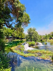 Serene River Landscape in Herzegovina with a Small Waterfall and Lush Greenery