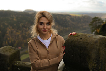 Woman in a beige outfit walking through a natural park with beautiful green cliffs on a cloudy day. Serene moment, connection with nature, stylish outdoor lifestyle.