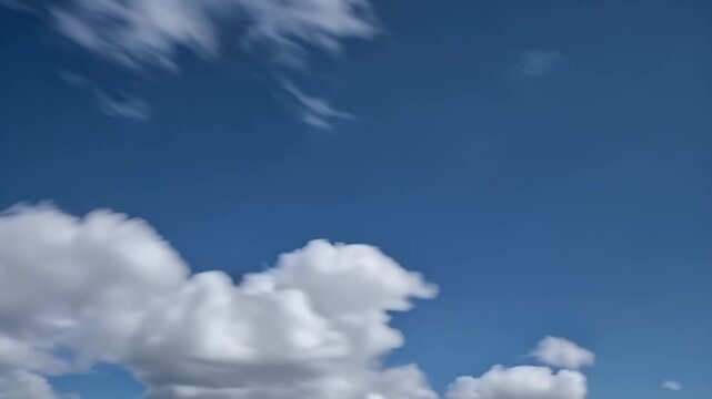 Smooth 4K time lapse capturing fast moving white clouds drifting from right to left across a bright blue sky with light motion blur perfect for overlay text titles or logo backgrounds in creative