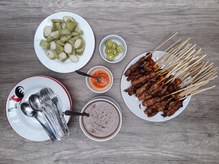 Sate Ayam (Chicken satay) served with rice cake, peanut sauce, chili sauce and lime. One of the popular Indonesian cuisine.