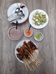 Sate Ayam (Chicken satay) served with rice cake, peanut sauce, chili sauce and lime. One of the popular Indonesian cuisine.