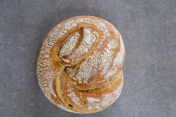 artisan bread with twisted top on stone surface, top view