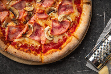 Pizza with ham and mushrooms on black stone table background