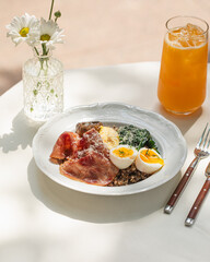 Breakfast plate with soft-boiled eggs, buckwheat, prosciutto and spinach under daylight