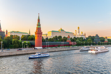 Obraz premium View of Kremlin with Vodovzvodnaya tower, Grand Kremlin Palace from repaired Bolshoy Kamenny Bridge in Moscow city on sunny summer day. Cruise ship sails on the Moscow river