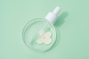 Cosmetic pipette serum on a petri dish on green background. Cosmetology and pharmaceuticals...