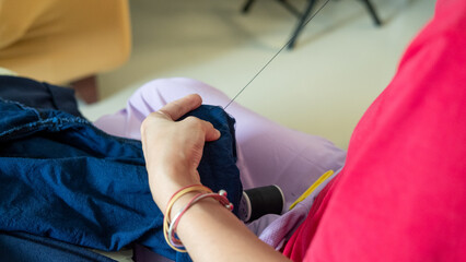 Close-up of a mother&rsquo;s hands sewing trouser legs, showing family care through homemade mending.