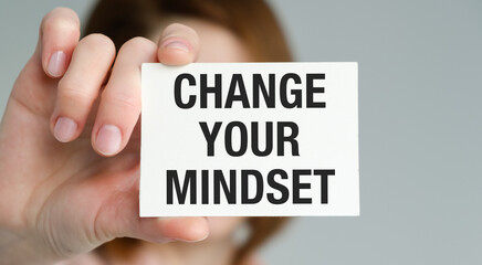 A person holding a white card that says Change Your Mindset