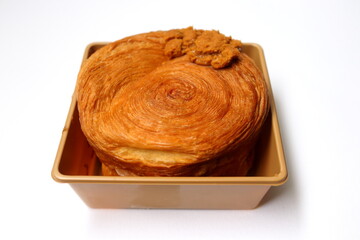A croissant roll or timber ring in golden color plastic box on white background.