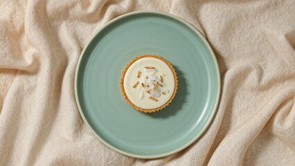 Top view of delicious coconut tart on elegant dish with textured fabric background