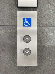 Up/down elevator buttons and wheelchair symbols on the cement wall.