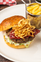 Homemade gourmet burger with crispy fried onions, bacon and French fries