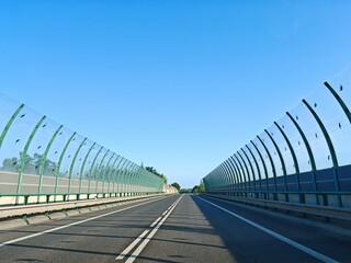 Fototapeta premium Glass and steel noise barriers placed along high-speed road near large city to reduce traffic noise.