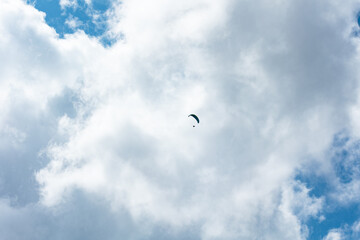 Flying paraglieder in the sky on a sunny day, clouds, Switzerland, Swiss Alps. Extreme sport, leisure activities, sunny day, outdoors, landscape.