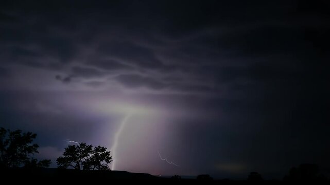 Intense thunderstorm with dramatic lightning strikes illuminating the dark purple night sky
