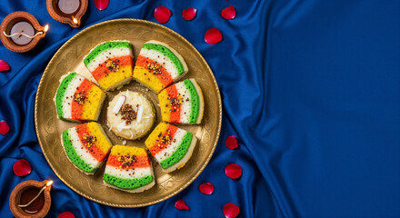 Flat lay of festive Indian food Tiranga Dhokla on a blue silk background with copy space for greetings