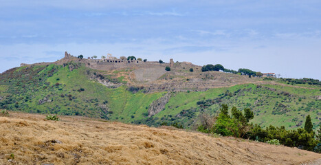 Wide panoramic view of ancient Pergamon ruins, highlighting the steep hillside amphitheater and the expansive landscape surrounding the historic site, Pergamon, Turkey.