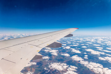 Obraz premium View from the airplane window at a beautiful cloudy sky and the airplane wing
