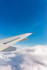 Fototapeta premium View from the airplane window at a beautiful cloudy sky and the airplane wing