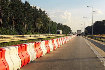 Long line of red and white plastic road barriers. Divided highway with traffic separation. Safety...