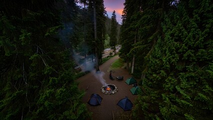 Aerial View: Campfire and Tents in Serene Twilight Forest Setting