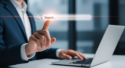 Businessman taps virtual search bar overlay on laptop in modern office, illustrating online query, digital search engine and SEO-driven web navigation concept