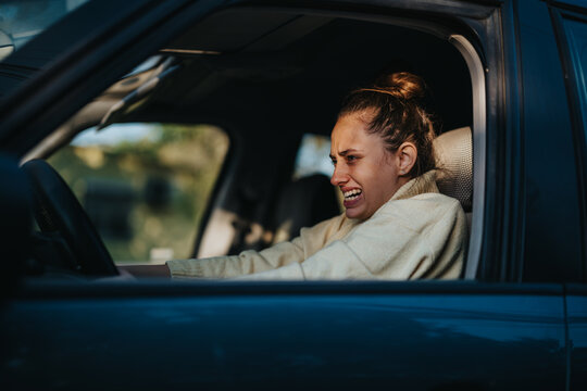 A woman sitting in a car looks stressed while gripping the steering wheel tightly. The emotional strain and frustration are evident, showcasing the challenges of daily commuting and traffic congestion