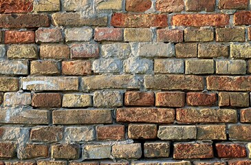 Background, texture of the wall of a house made of old bricks of different shades of red