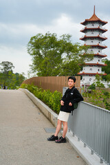 A young Asian man stands on the steps leading up to a multi-tiered traditional Chinese pagoda